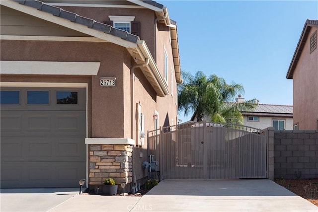 26718 Cactus Creek Way, Menifee, CA 92586 - view of side of property featuring stucco siding, a garage, a gate, concrete driveway, and stone siding