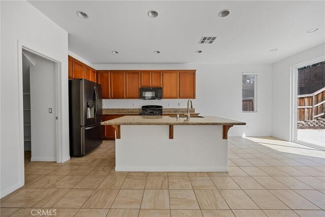 34135 Crenshaw St, Beaumont, CA 92223 - kitchen with black microwave, fridge with ice dispenser, range, light stone countertops, and an island with sink