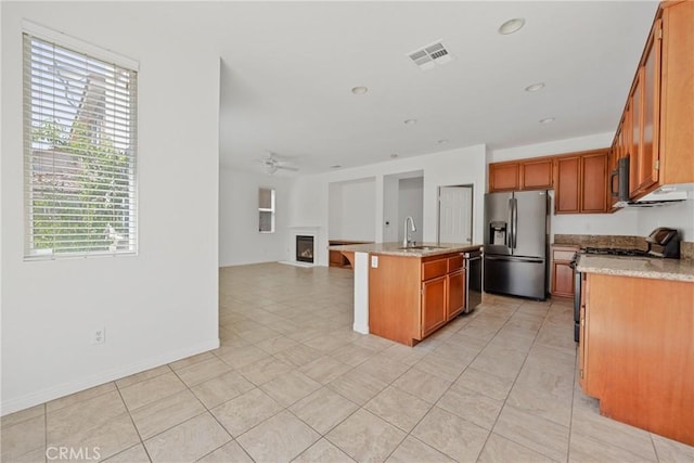 34135 Crenshaw St, Beaumont, CA 92223 - kitchen featuring stainless steel appliances, open floor plan, an island with sink, a ceiling fan, and brown cabinetry