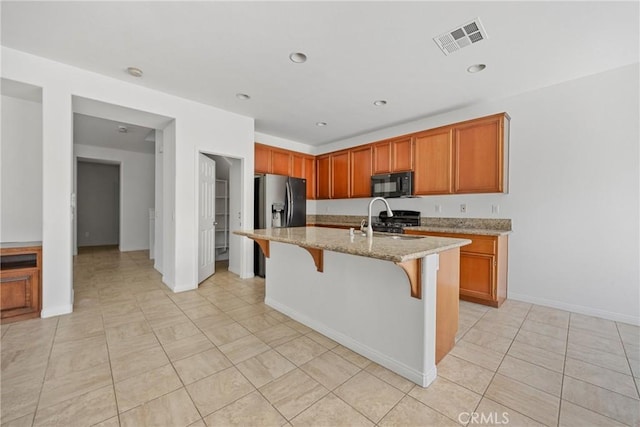 34135 Crenshaw St, Beaumont, CA 92223 - kitchen featuring black microwave, range, light stone counters, a kitchen bar, and light tile patterned flooring
