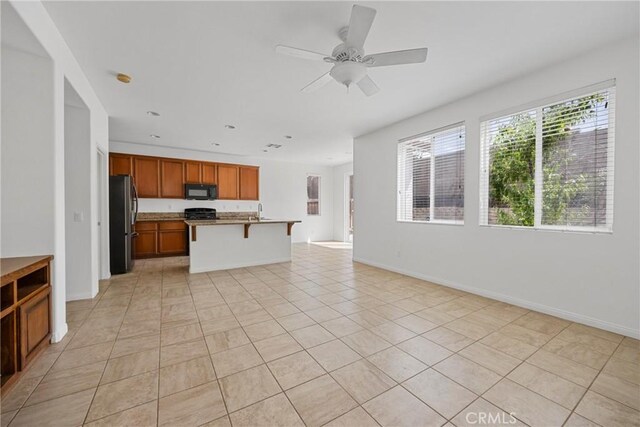 34135 Crenshaw St, Beaumont, CA 92223 - kitchen with freestanding refrigerator, open floor plan, black microwave, brown cabinets, and a kitchen bar