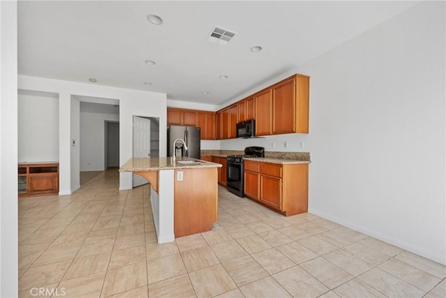 34135 Crenshaw St, Beaumont, CA 92223 - kitchen with black appliances, light stone counters, light tile patterned floors, a center island with sink, and a breakfast bar area