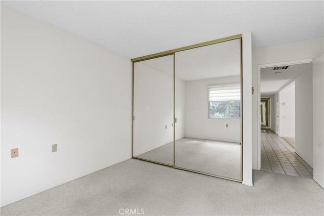 unfurnished bedroom with a closet, carpet, and visible vents