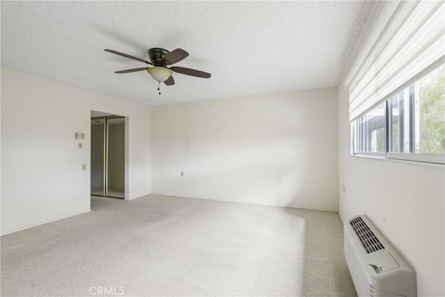 carpeted spare room featuring a textured ceiling, ceiling fan, and a wall unit AC
