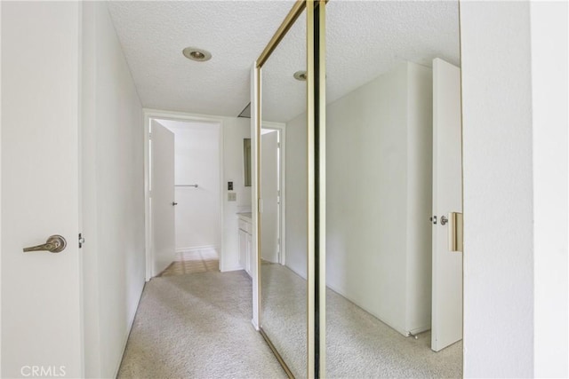 hall with light carpet and a textured ceiling