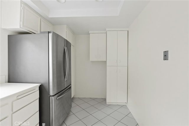 kitchen featuring white cabinetry, light countertops, light tile patterned floors, and freestanding refrigerator