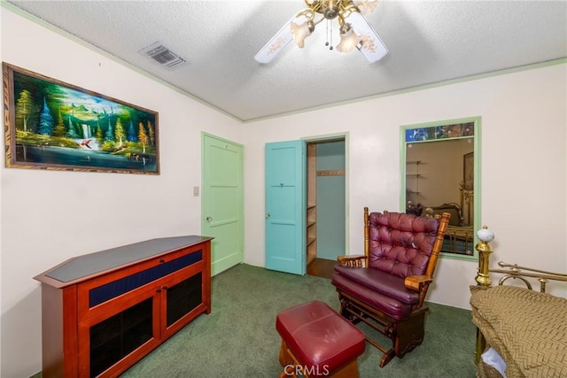 living area with a textured ceiling, dark carpet, ceiling fan, and visible vents
