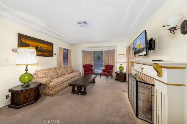 living room with a textured ceiling, visible vents, carpet, and a fireplace