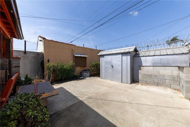 view of patio / terrace featuring an outdoor structure, fence, and a storage shed