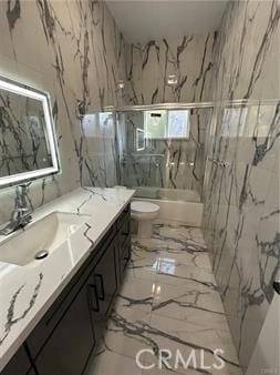 full bathroom featuring marble finish floor, toilet, vanity, and shower / bath combination with glass door