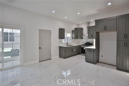 kitchen with a sink, plenty of natural light, gas range, marble finish floor, and backsplash