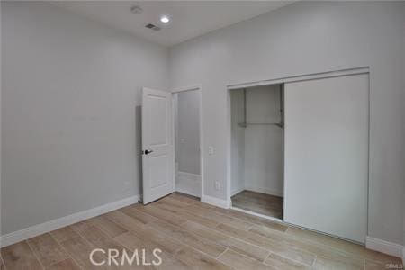 unfurnished bedroom with a closet, visible vents, recessed lighting, wood finished floors, and baseboards