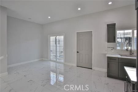 kitchen with marble finish floor, a sink, baseboards, and recessed lighting