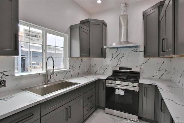 kitchen featuring gray cabinetry, gas range, wall chimney exhaust hood, and a sink