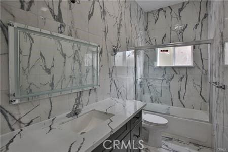 full bathroom featuring enclosed tub / shower combo, vanity, marble finish floor, and toilet