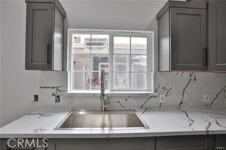 kitchen featuring a sink, gray cabinetry, and backsplash