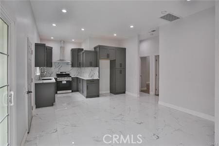 kitchen featuring baseboards, stainless steel range oven, wall chimney range hood, recessed lighting, and marble finish floor