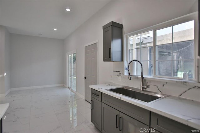 kitchen with gray cabinets, marble finish floor, a sink, and baseboards