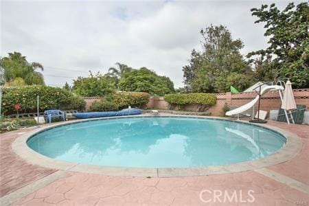 view of pool with a fenced in pool, fence, and a water slide