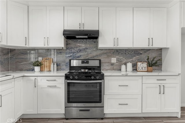 kitchen with light wood finished floors, tasteful backsplash, white cabinetry, stainless steel gas stove, and under cabinet range hood