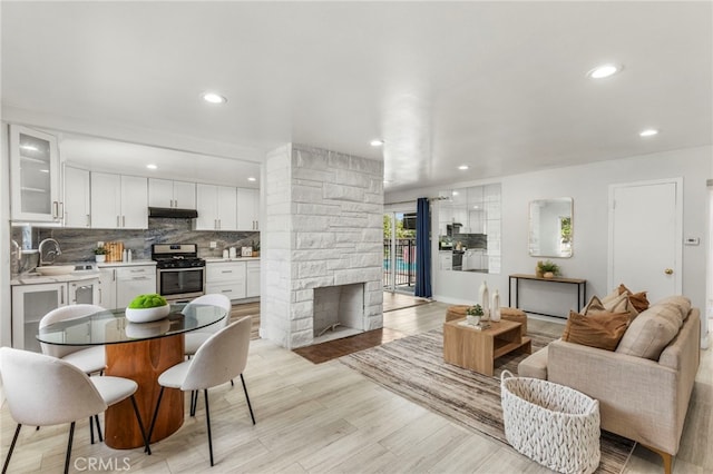 living area with a fireplace, light wood finished floors, and recessed lighting
