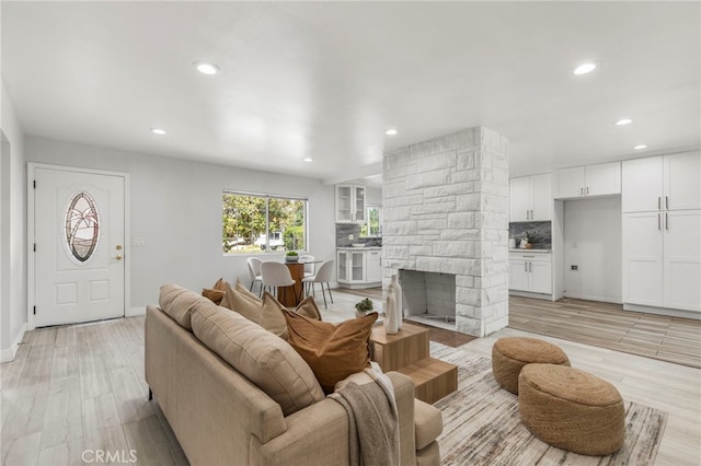 living area with a fireplace, baseboards, recessed lighting, and light wood-style floors