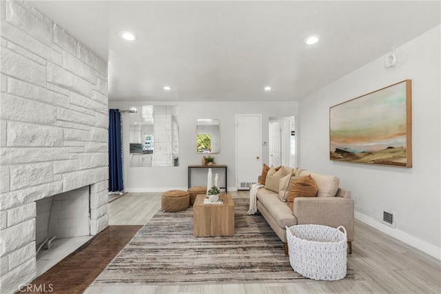 living room with baseboards, a stone fireplace, wood finished floors, and recessed lighting