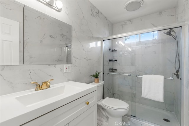 bathroom with a shower stall, toilet, vanity, and tile walls