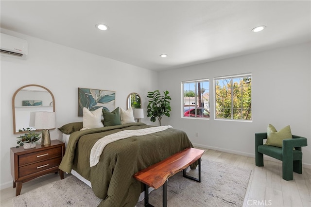 bedroom featuring recessed lighting, baseboards, light wood finished floors, and a wall unit AC