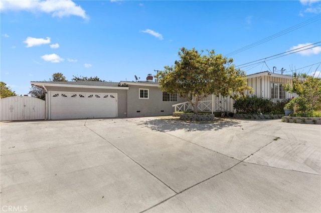 view of front of property featuring an attached garage, stucco siding, a gate, and concrete driveway