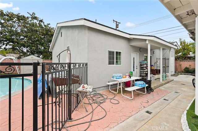 back of house with a patio area, a fenced backyard, a fenced in pool, and stucco siding
