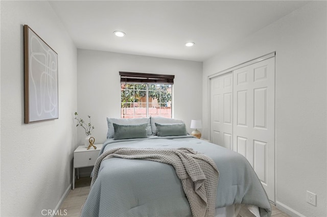 bedroom with recessed lighting, baseboards, light wood-type flooring, and a closet