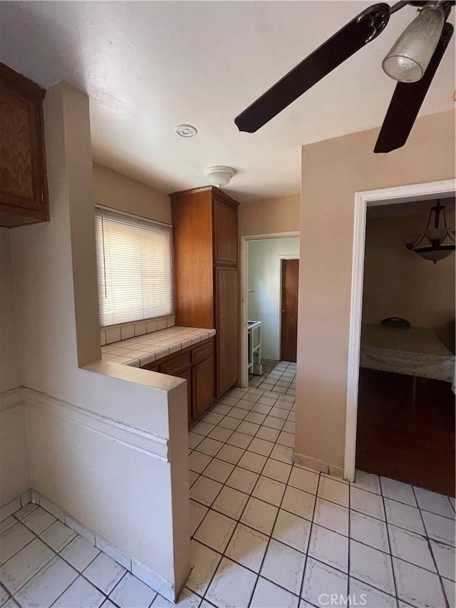 3509 Greenglade Ave, Pico Rivera, CA 90660 - kitchen featuring tile counters, light tile patterned floors, and brown cabinetry