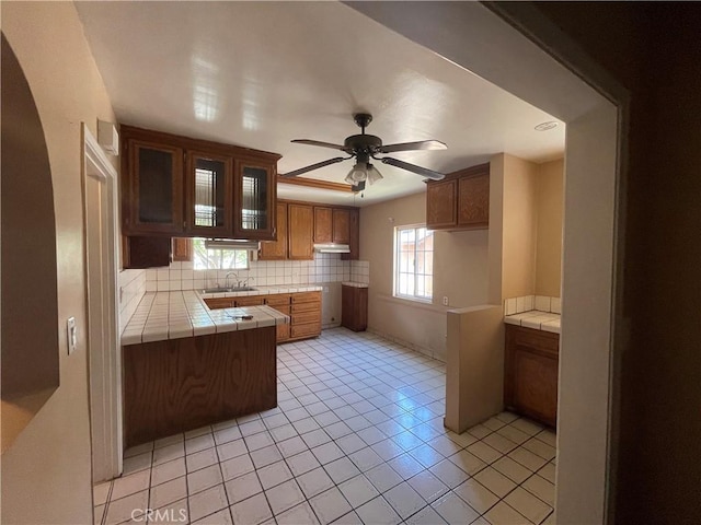 3509 Greenglade Ave, Pico Rivera, CA 90660 - kitchen featuring tile countertops, a sink, decorative backsplash, a ceiling fan, and brown cabinetry