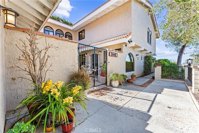 exterior space featuring a gate, stucco siding, and fence