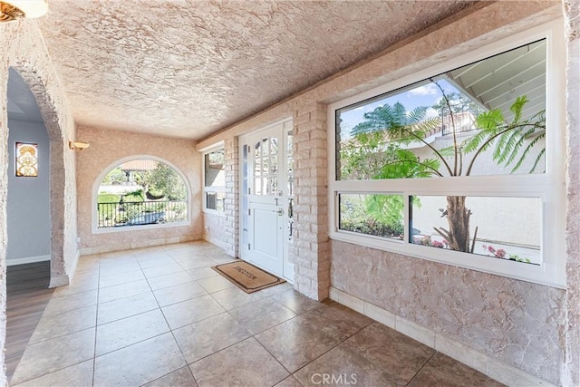 foyer entrance featuring tile patterned floors, baseboards, and a textured ceiling