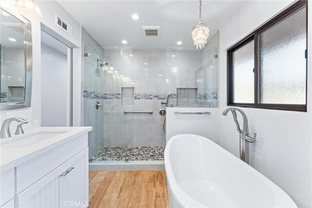 bathroom with a freestanding tub, a shower stall, wood finished floors, and visible vents