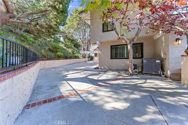 view of side of property with a patio, fence, and stucco siding