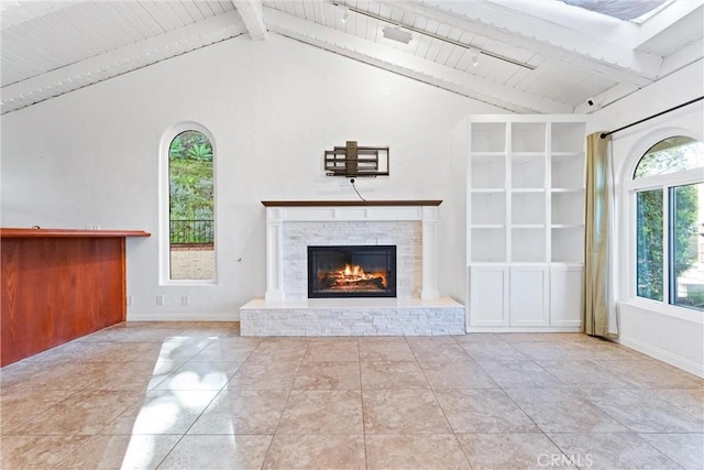 unfurnished living room with a healthy amount of sunlight, vaulted ceiling with beams, and a fireplace