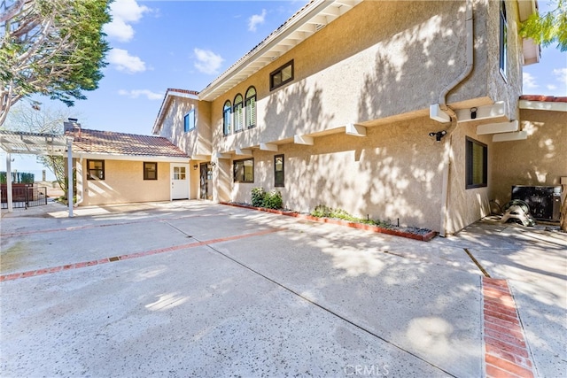 back of house featuring a pergola, a patio area, and stucco siding