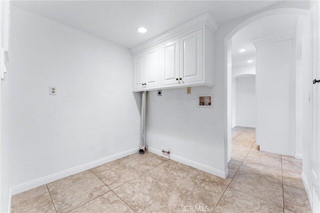 clothes washing area with baseboards, hookup for an electric dryer, arched walkways, washer hookup, and hookup for a gas dryer