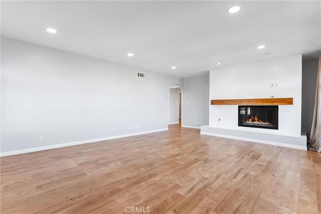 604 Avenida Acapulco, San Clemente, CA 92672 - unfurnished living room featuring arched walkways, a glass covered fireplace, recessed lighting, light wood-type flooring, and baseboards