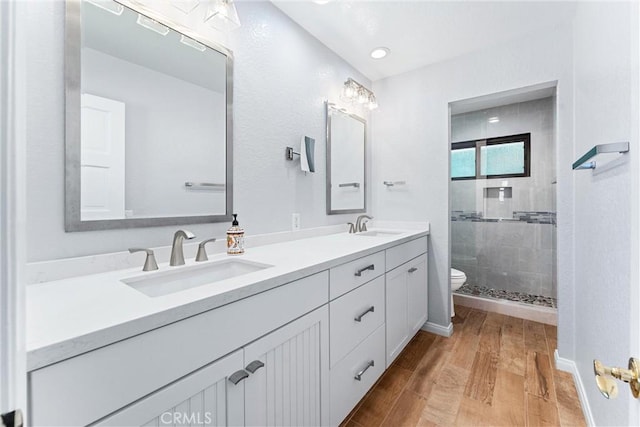 full bath with toilet, a shower stall, a sink, and wood finished floors