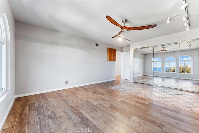 unfurnished living room featuring ceiling fan, visible vents, track lighting, baseboards, and light wood-style flooring