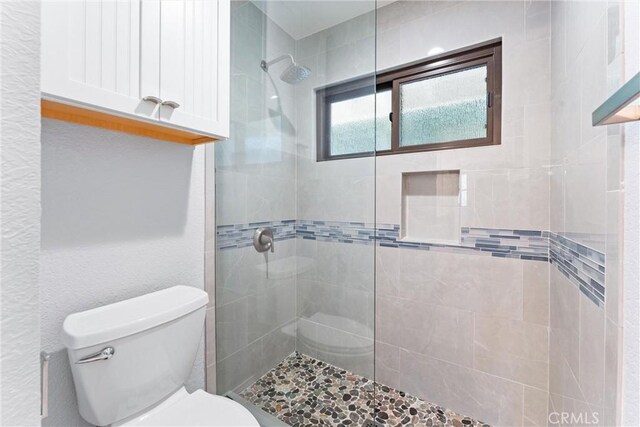 bathroom with toilet and tiled shower