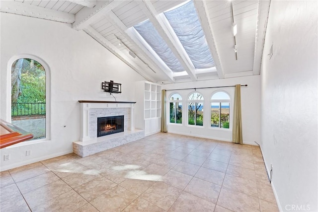 unfurnished living room featuring rail lighting, baseboards, wooden ceiling, a glass covered fireplace, and vaulted ceiling with beams