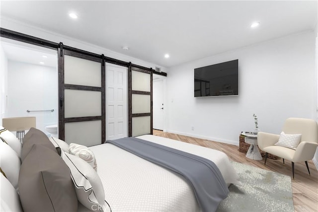 bedroom featuring baseboards, ensuite bathroom, recessed lighting, a barn door, and light wood-style flooring