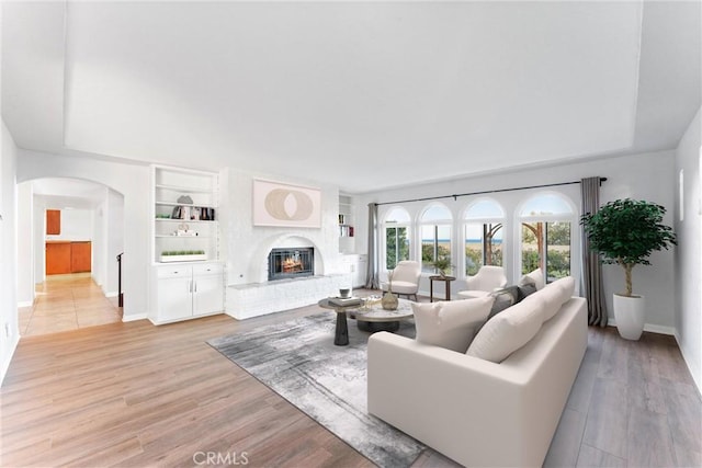 604 Avenida Acapulco, San Clemente, CA 92672 - living room with baseboards, built in features, a brick fireplace, arched walkways, and light wood-style flooring