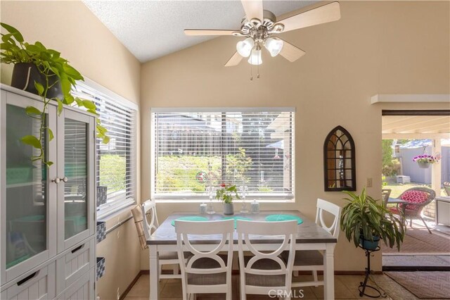 dining space featuring baseboards, a ceiling fan, tile patterned flooring, and vaulted ceiling
