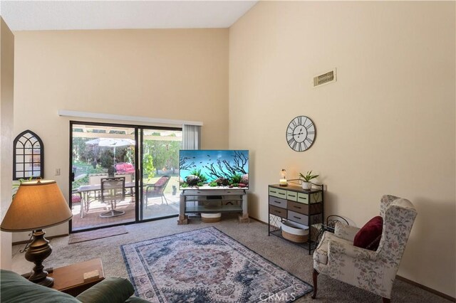 living area with carpet flooring, a high ceiling, visible vents, and baseboards
